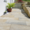 Terrassenplatten in Beige-Grau entlang eines Hauswegs, mit Pflanzkübeln und beiger Mauer