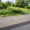 Grau gemauerte Mauer mit Abdeckplatte vor bepflanzter Gartenanlage und gepflastertem Weg