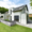 Graue Mauer als Hochbeet vor modernem Haus mit Terrasse und Gartenweg, Tribus