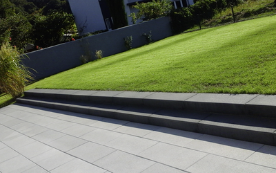 Graue Blockstufen an einer Terrasse mit angrenzender Rasenfläche