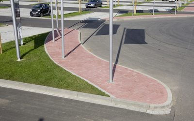 Bordstein-Absenker aus grauem Beton, rund verlegt an einer rot gepflasterten Verkehrsinsel im Außenbereich
