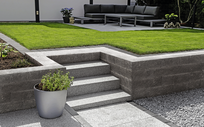 Mauerblock aus Beton für Gartenmauer, dunkelgrau, mit Treppe und Rasen im Außenbereich