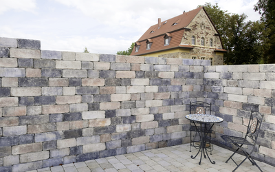 Muschelkalk Mauer und gepflasterte Terrasse mit Tisch und Stuhl