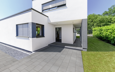 Graue Pflastersteine auf der Terrasse vor einem modernen Haus, mit Gartenweg und Rasen