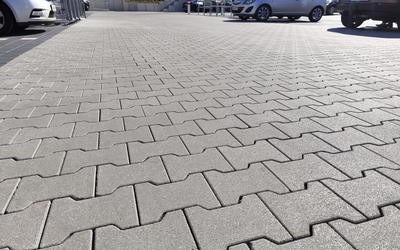 Doppel-T-Pflaster aus grauem Beton, verlegt auf einer befestigten Fläche im Außenbereich