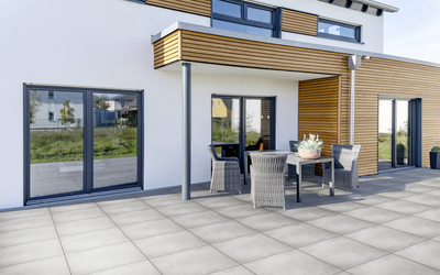 Grau geflieste Terrasse vor einem modernen Haus mit Sitzgruppe