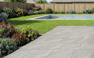 Graue Terrassenplatten mit feiner Struktur neben Pool und Gartenbeet