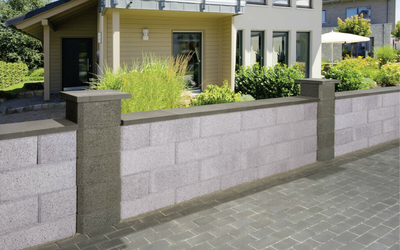 Gartenmauer aus grauen Betonsteinen mit anthrazitfarbenen Pfeilern