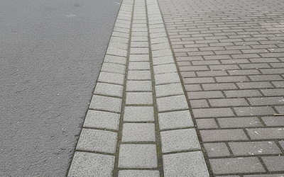 Graue Rinnenpflaster-Steine in einer schmalen Entwässerungsrinne entlang der Straße