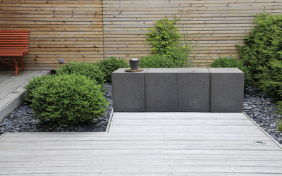 Graue Sitzbank aus vier Elementen auf Holzterrasse im Garten