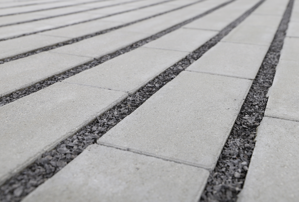 Graue Betonplatten mit schmalen Splittfugen, in Reihen verlegt