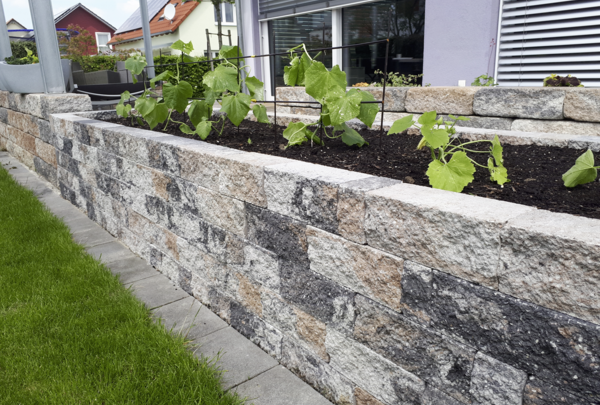 Muschelkalk-Mauer im Garten mit bepflanztem Hochbeet und Natursteinoptik