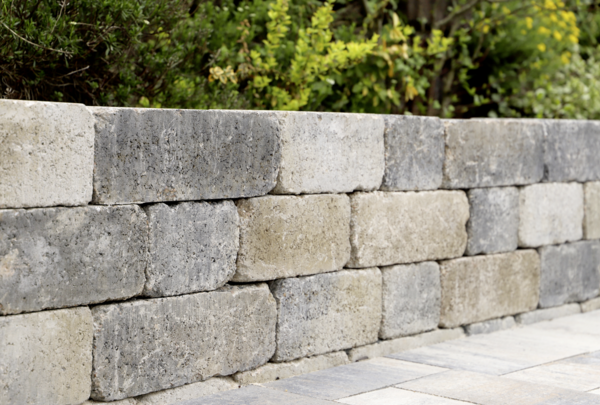 Natursteinmauer aus hellgrauen und beigen Quadern mit Pflaster im Vordergrund