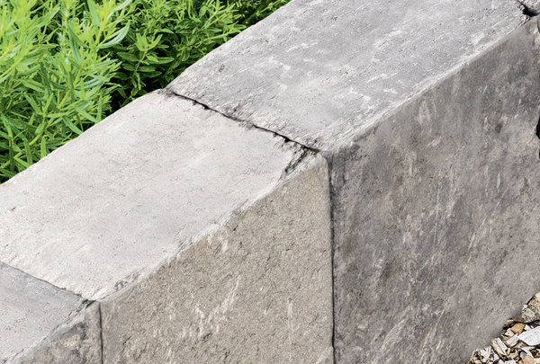 graue Betonpalisade mit strukturierter Oberfläche als Beetbegrenzung im Garten
