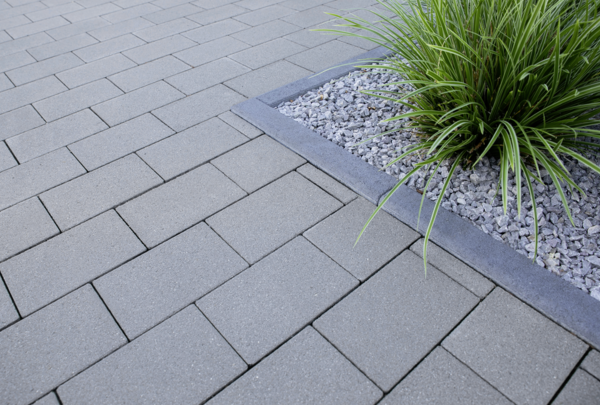 Graue Pflastersteine auf Terrasse mit Beetrand aus Beton und Kies