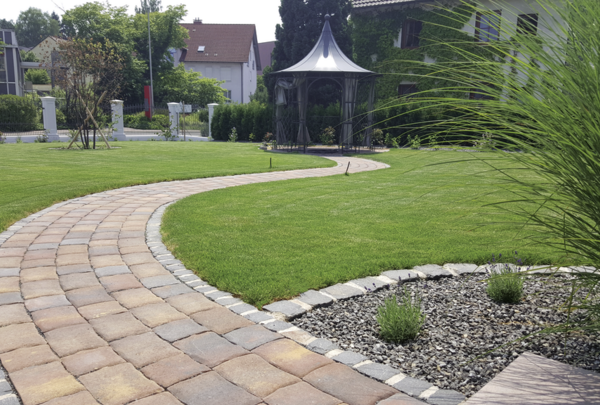 Geschwungener Pflasterweg mit dem Altstadtpflaster durch eine Gartenanlage