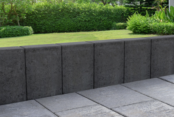 Anthrazitfarbene Betonmauer zur Flächentrennung an einer Terrasse im Garten, Palibord