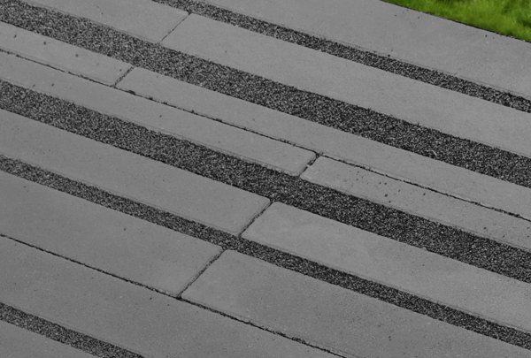 Anthrazitfarbene Dränsteine im Gartenweg, mit breiten Kiesfugen verlegt