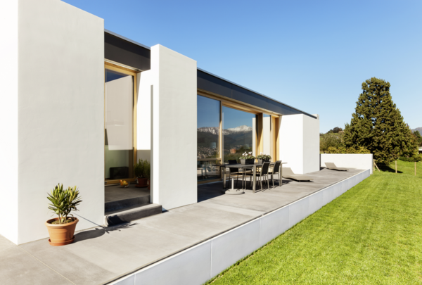Moderne Terrassenanlage mit weißen Stützwinkeln, grauen Platten und angrenzendem Rasen