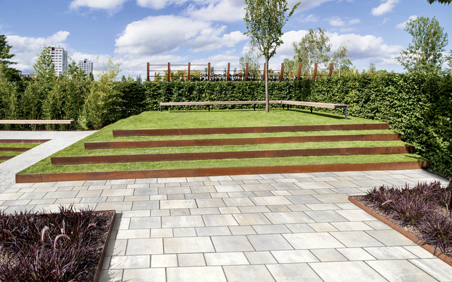 Terrassenbelag aus hellen Pflastersteinen vor gestuftem Gründach im Garten