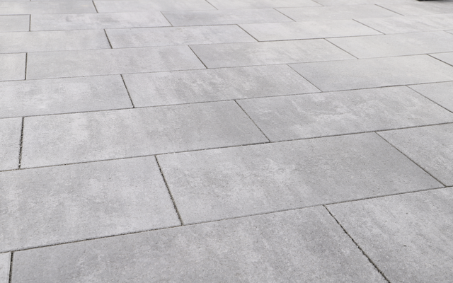 Graue Betonplatten mit nuancierter Oberfläche als Terrassenbelag im Garten- und Landschaftsbau