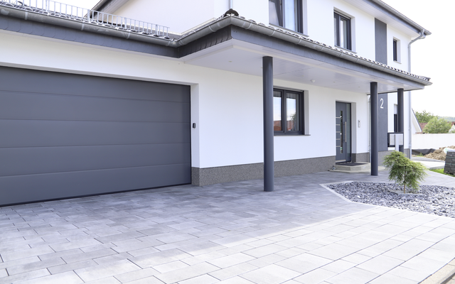 Pflastersteine vor moderner Hauszufahrt mit Garage, grau-anthrazit nuanciert