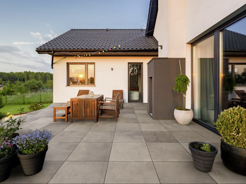Großformatige graue Terrassenplatten in modernem Außenbereich neben einem Haus