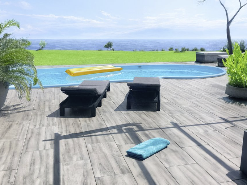 Großformatige graue Terrassenplatten am Pool mit Liegen und Meerblick