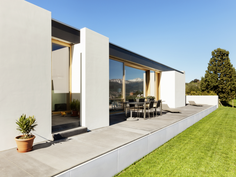 Moderne Terrassenanlage mit weißen Stützwinkeln, grauen Platten und angrenzendem Rasen