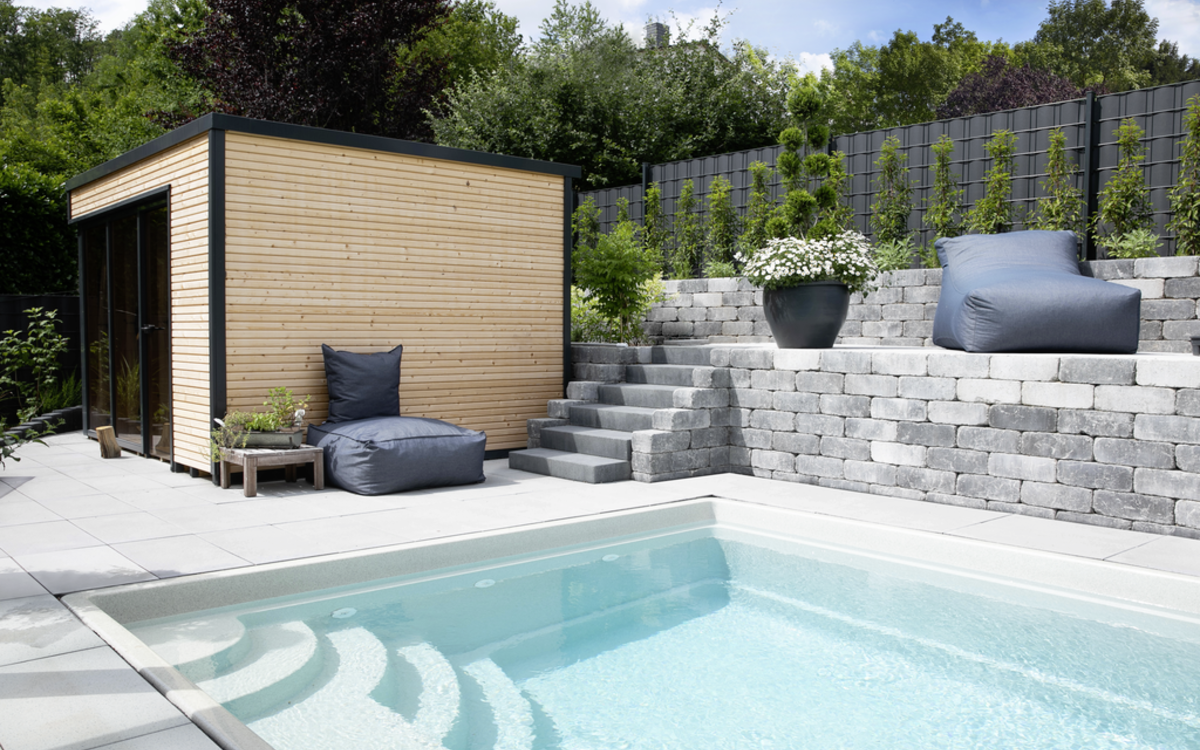 graue Mauerelemente als Stützmauer am Pool mit Stufen im Garten