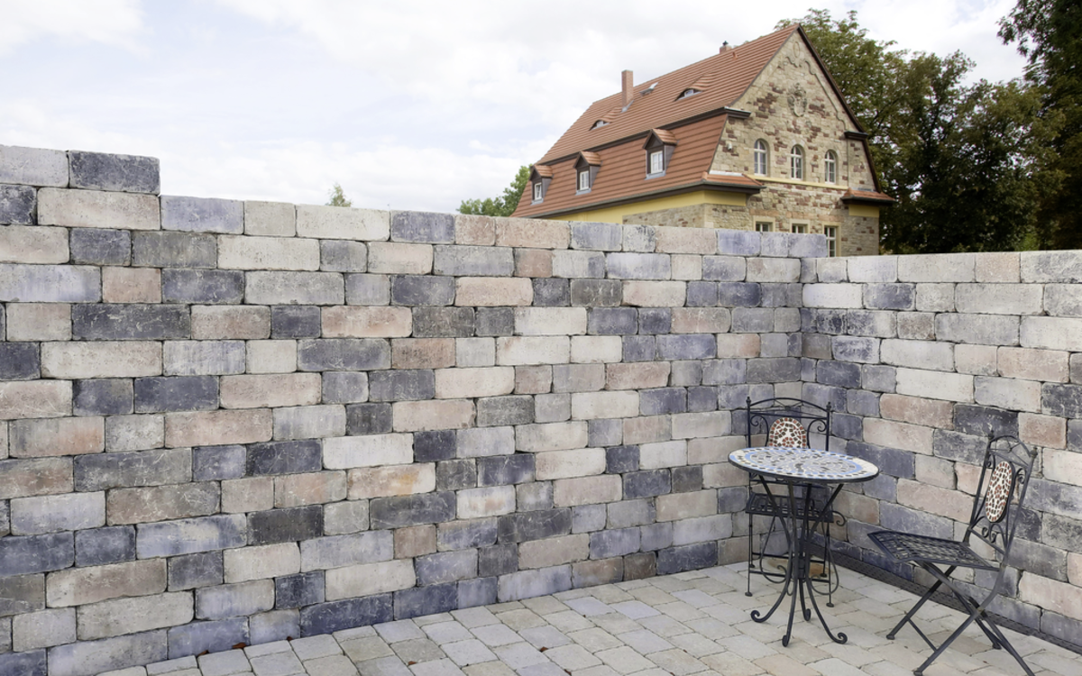 Muschelkalk Mauer und gepflasterte Terrasse mit Tisch und Stuhl