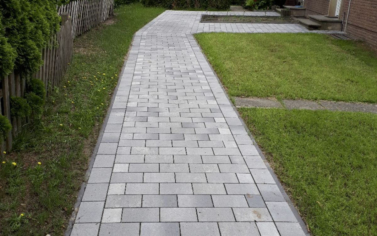 grau-anthrazit nuancierter Pflasterweg im Garten entlang eines Hauses