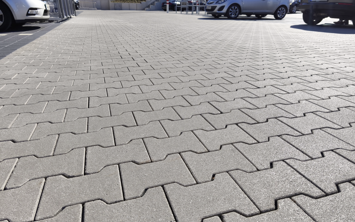 Doppel-T-Pflaster aus grauem Beton, verlegt auf einer befestigten Fläche im Außenbereich