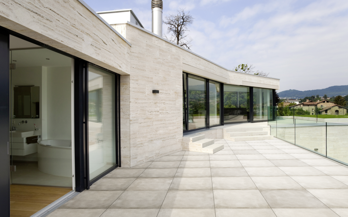 Großformatige helle Terrassenplatten auf moderner Außenanlage mit Glasgeländer
