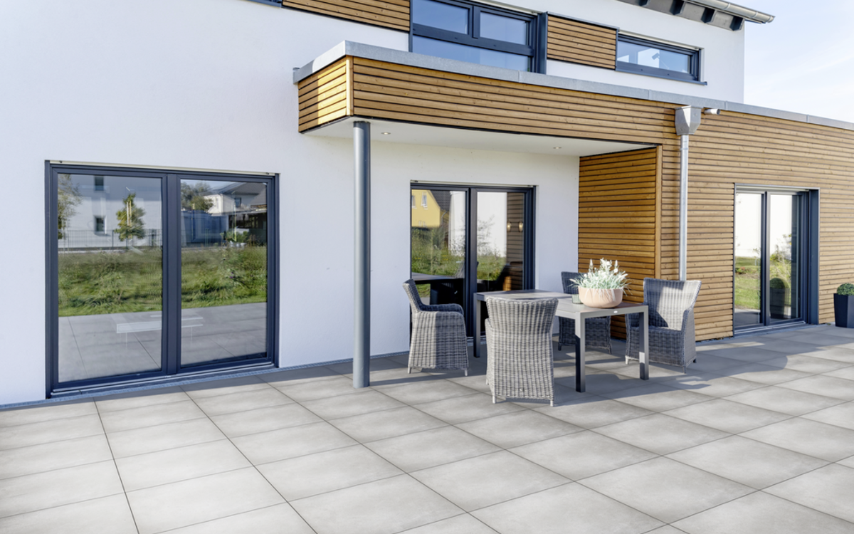 Grau geflieste Terrasse vor einem modernen Haus mit Sitzgruppe