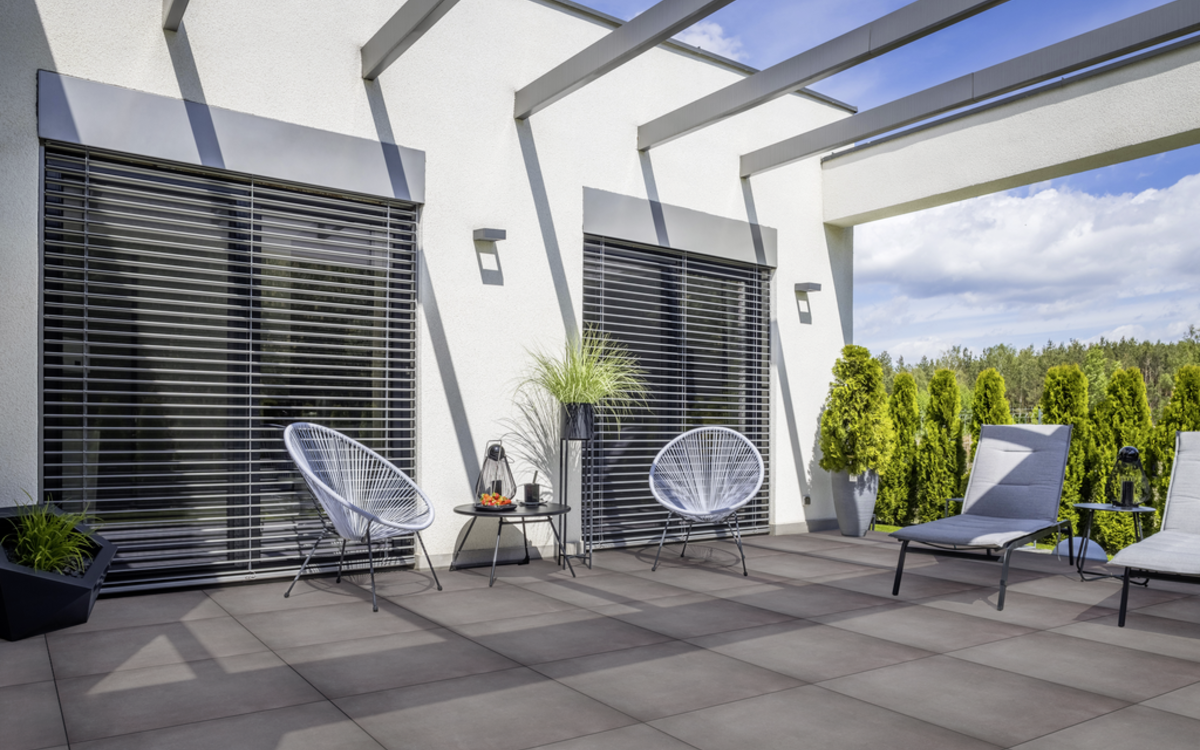 Großformatige Keramikplatten auf Terrasse vor moderner Hausfassade, grau verlegt