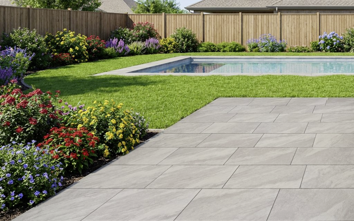 Graue Terrassenplatten mit feiner Struktur neben Pool und Gartenbeet