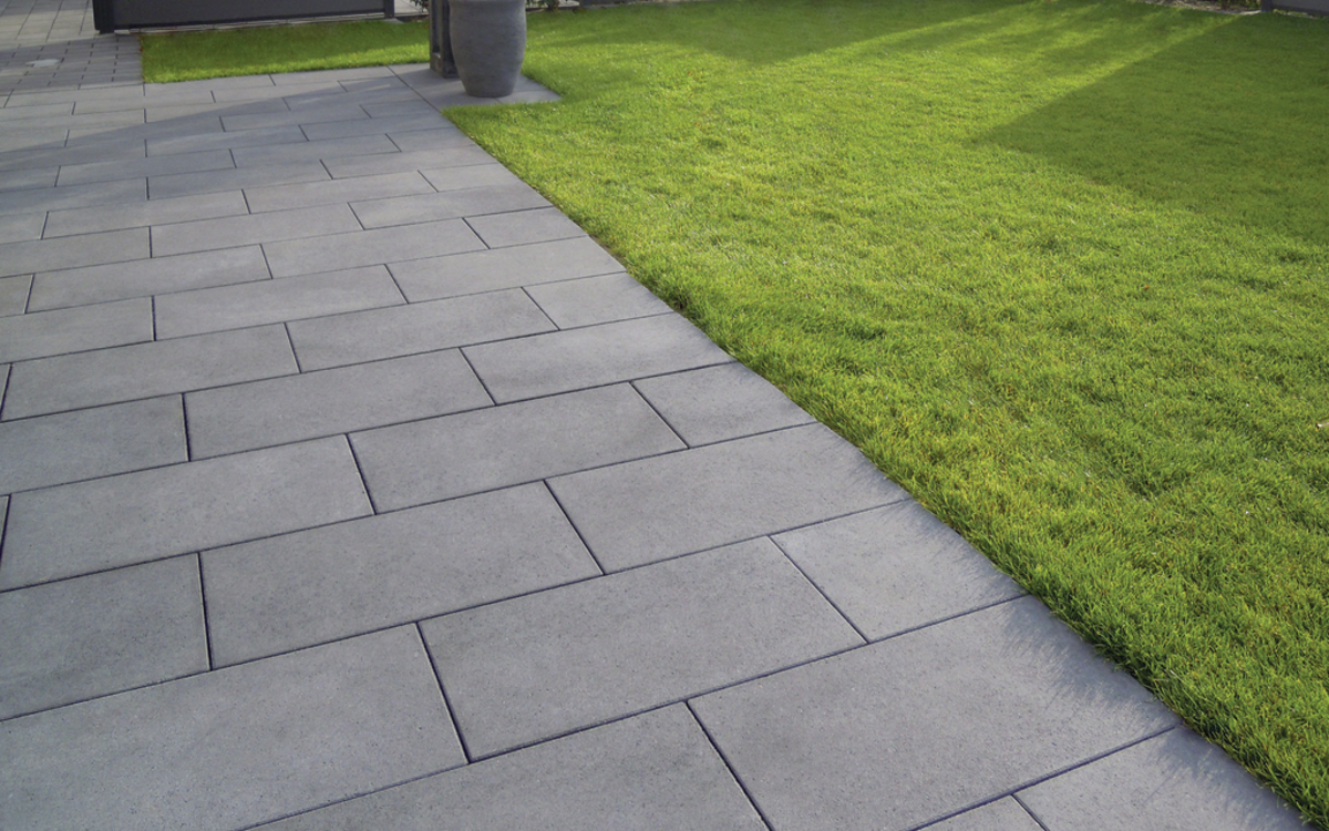 Anthrazitfarbene Terrassenplatten an Rasenfläche im Garten