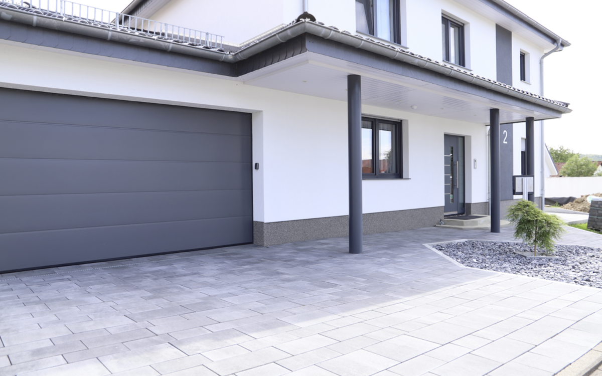 Pflastersteine vor moderner Hauszufahrt mit Garage, grau-anthrazit nuanciert
