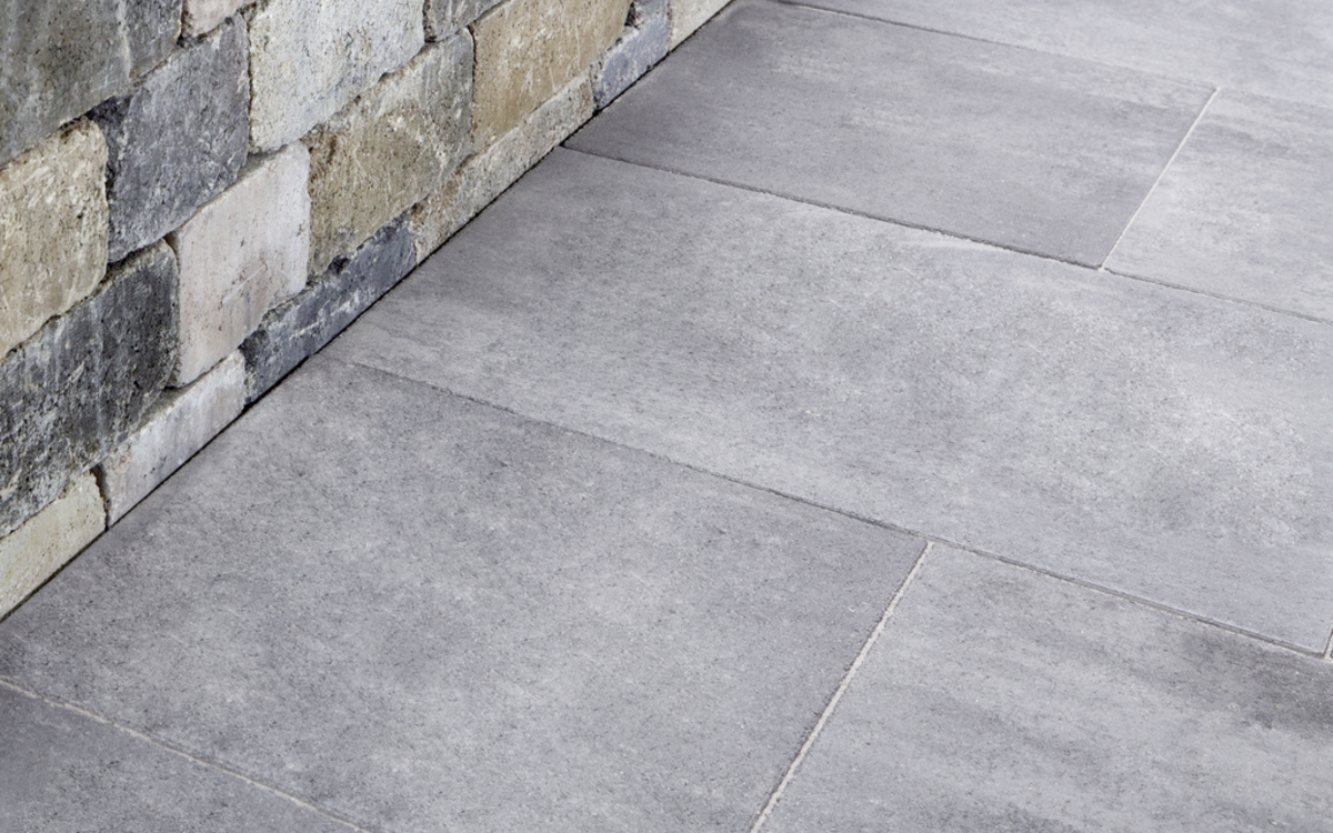 Großformatige graue Terrassenplatten aus Beton neben einer nuancierten Mauer